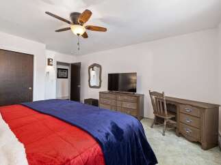 This cozy bedroom features a comfortable bed with vibrant red and blue bedding, perfect for relaxation.