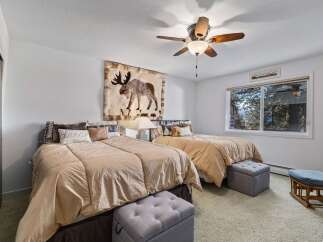 This charming bedroom features two comfortable beds adorned with plush bedding and decorative pillows, perfect for a restful night's sleep.