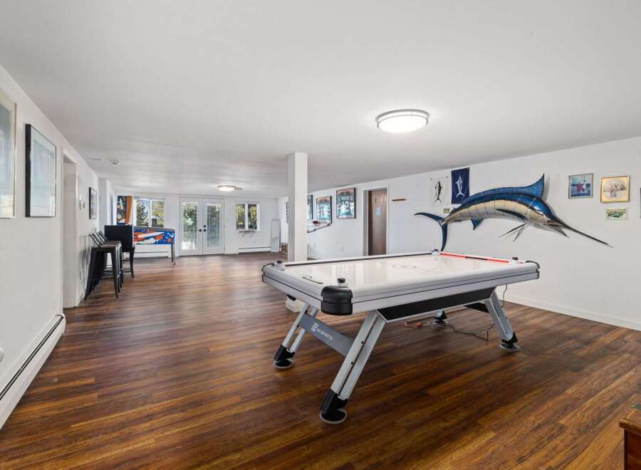 This spacious basement recreation room offers endless entertainment possibilities with a large air hockey table and a vintage pinball machine.