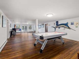 This spacious basement recreation room offers endless entertainment possibilities with a large air hockey table and a vintage pinball machine.