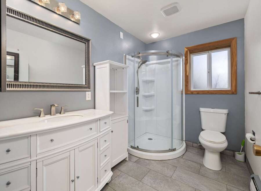 This modern bathroom features a spacious vanity with ample storage and a marble countertop, complemented by a large, ornate mirror.
