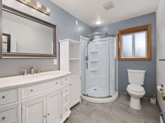 This modern bathroom features a spacious vanity with ample storage and a marble countertop, complemented by a large, ornate mirror.