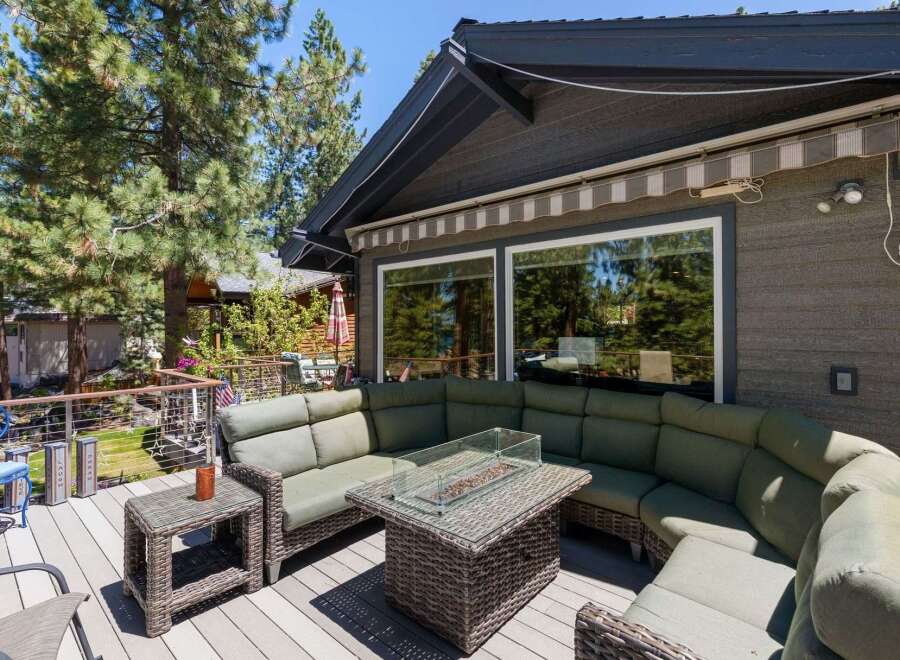 Enjoy outdoor living at its finest on this spacious deck, featuring a large sectional sofa and a stylish fire pit table perfect for gathering with loved ones.