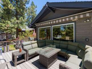 Enjoy outdoor living at its finest on this spacious deck, featuring a large sectional sofa and a stylish fire pit table perfect for gathering with loved ones.