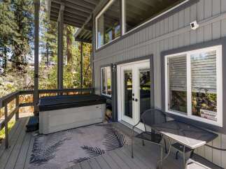 Enjoy outdoor living with this spacious deck featuring a relaxing hot tub and a charming patio set.