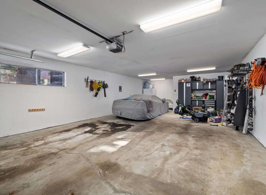 This spacious garage offers ample storage and parking solutions, featuring a car cover for protection and a wall-mounted tool organizer.