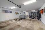 This spacious garage offers ample storage and parking solutions, featuring a car cover for protection and a wall-mounted tool organizer.