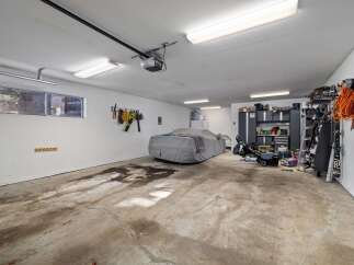This spacious garage offers ample storage and parking solutions, featuring a car cover for protection and a wall-mounted tool organizer.