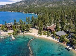 Experience luxury lakeside living with this stunning property featuring a private sandy beach and crystal-clear turquoise waters.