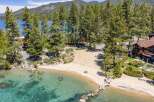 Experience luxury lakeside living with this stunning property featuring a private sandy beach and crystal-clear turquoise waters.
