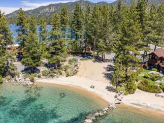 Experience luxury lakeside living with this stunning property featuring a private sandy beach and crystal-clear turquoise waters.