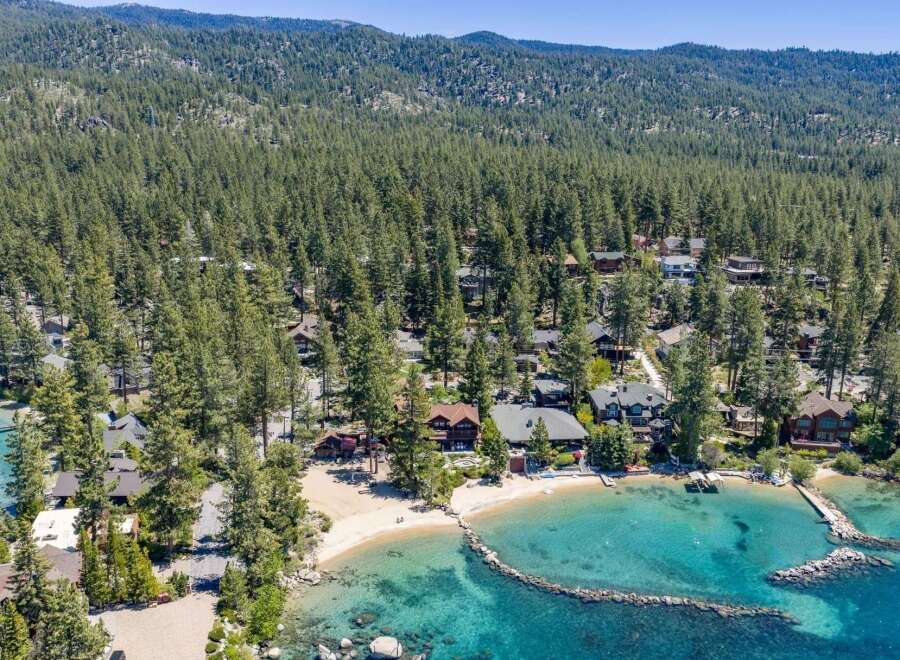 Experience luxury lakeside living with this stunning aerial view of a private beach and crystal-clear turquoise waters.