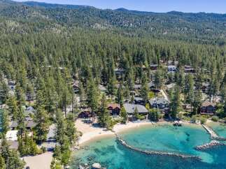 Experience luxury lakeside living with this stunning aerial view of a private beach and crystal-clear turquoise waters.