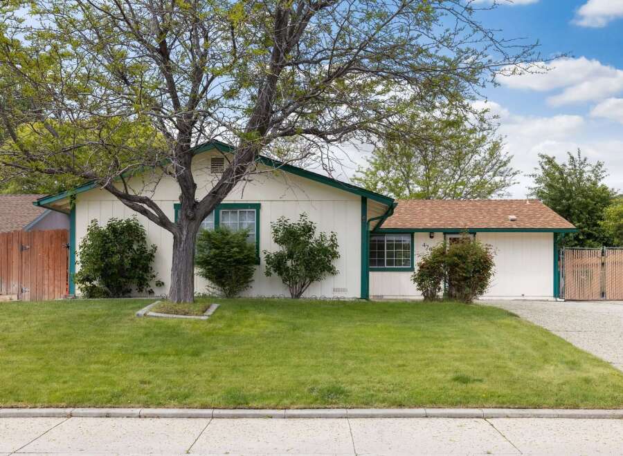 Charming single-story home with a welcoming facade, featuring a well-maintained lawn and mature trees.