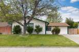 Charming single-story home with a welcoming facade, featuring a well-maintained lawn and mature trees.