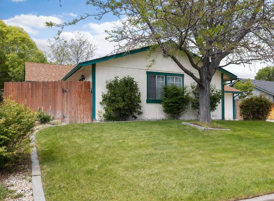 Charming single-story home featuring a welcoming front yard with lush green grass and mature trees.