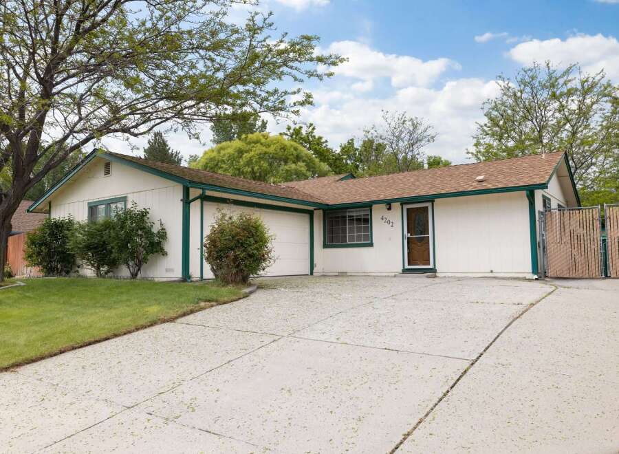 Charming single-story home with a welcoming facade, featuring a well-maintained lawn and mature trees.