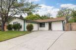 Charming single-story home with a welcoming facade, featuring a well-maintained lawn and mature trees.