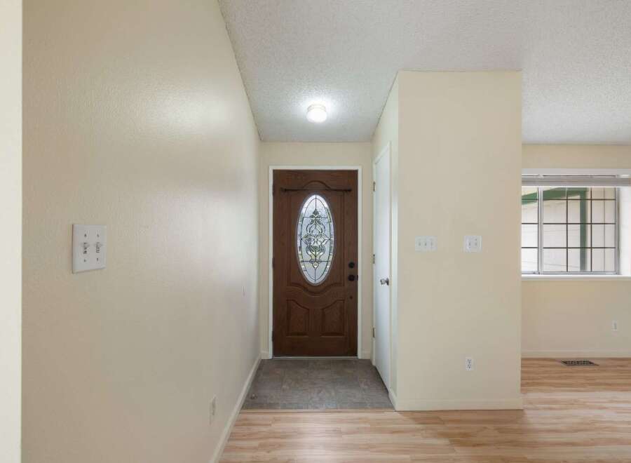 Step into a welcoming entryway featuring a beautiful wooden front door with decorative glass accents.