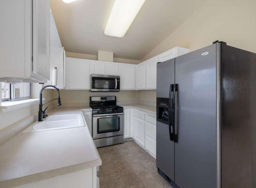 This charming kitchen features sleek white cabinetry and a spacious double sink with a modern gooseneck faucet.