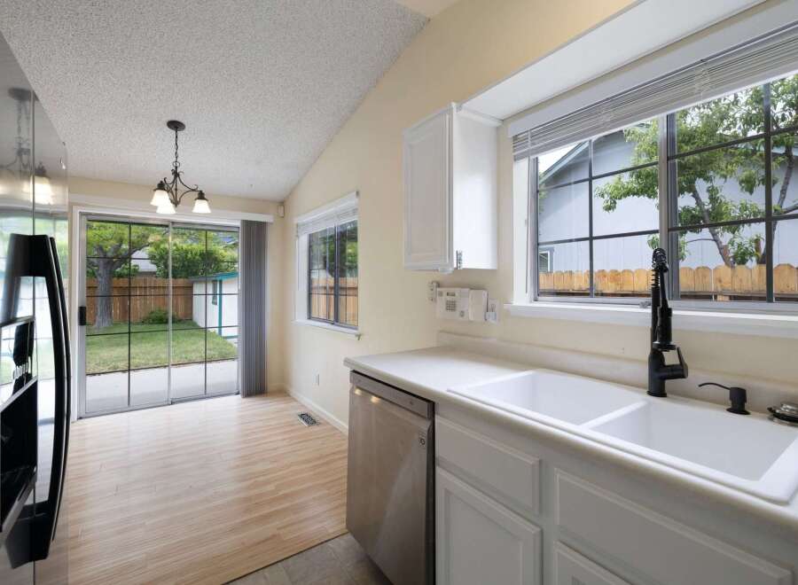 This kitchen features a spacious double sink with a modern black faucet, complemented by a stainless steel dishwasher.