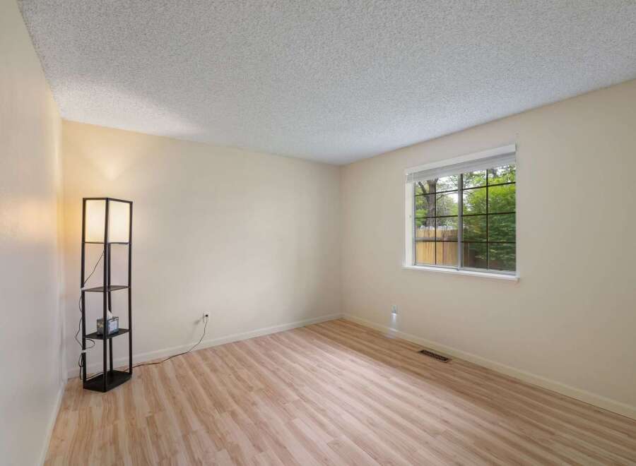 This empty room features light-colored walls and a wood-look laminate floor, creating a bright and airy atmosphere.