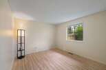 This empty room features light-colored walls and a wood-look laminate floor, creating a bright and airy atmosphere.