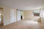 Discover this spacious room featuring a modern white sliding barn door leading to a bathroom.