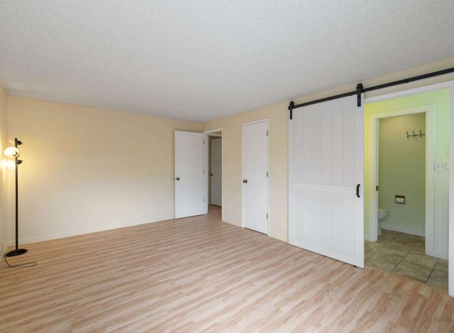 Step into this spacious room featuring a modern sliding barn door that leads to a private bathroom.