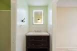 This bathroom features a modern vanity with a sleek white countertop and a dark wood cabinet, complemented by a bright LED-lit mirror.