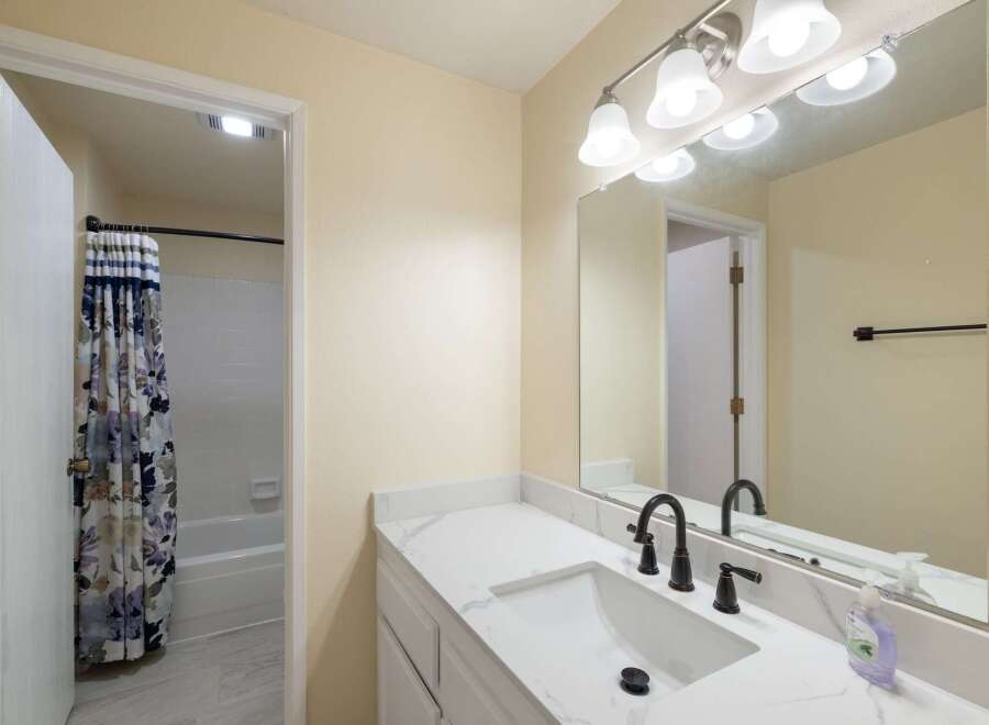 This bathroom features a sleek white vanity with a marble-look countertop and a modern black faucet.