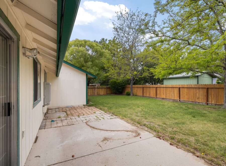 Enjoy outdoor living in this spacious backyard featuring a concrete patio and a well-maintained lawn, perfect for relaxation and recreation.