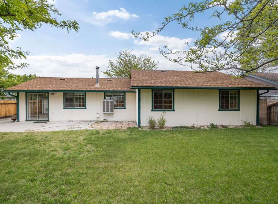 This charming single-story home features a spacious backyard with a patio area, perfect for outdoor entertaining.