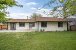 This charming single-story home features a spacious backyard with a patio area, perfect for outdoor entertaining.