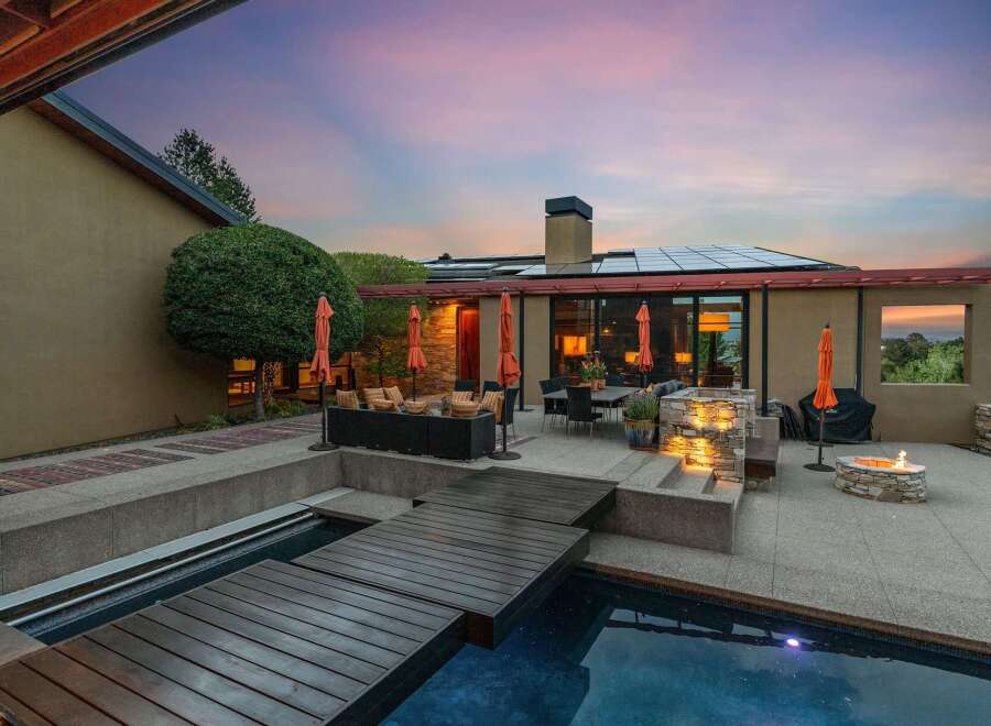 Experience luxurious outdoor living with this stunning backyard oasis, featuring a sparkling pool and a modern wooden deck perfect for relaxation and entertaining.
