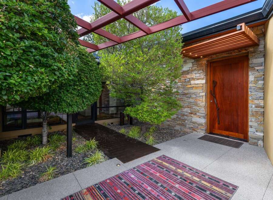 This modern entryway features a striking wooden door set against a stacked stone facade, creating a warm and inviting entrance.