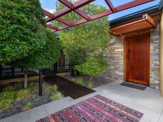 This modern entryway features a striking wooden door set against a stacked stone facade, creating a warm and inviting entrance.