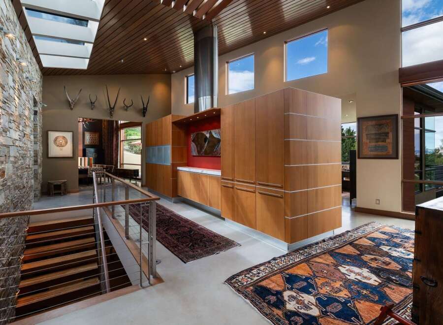 Experience luxurious living in this stunning modern home featuring a dramatic stone accent wall and a soaring wood-paneled ceiling with skylights.