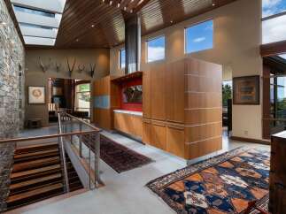 Experience luxurious living in this stunning modern home featuring a dramatic stone accent wall and a soaring wood-paneled ceiling with skylights.