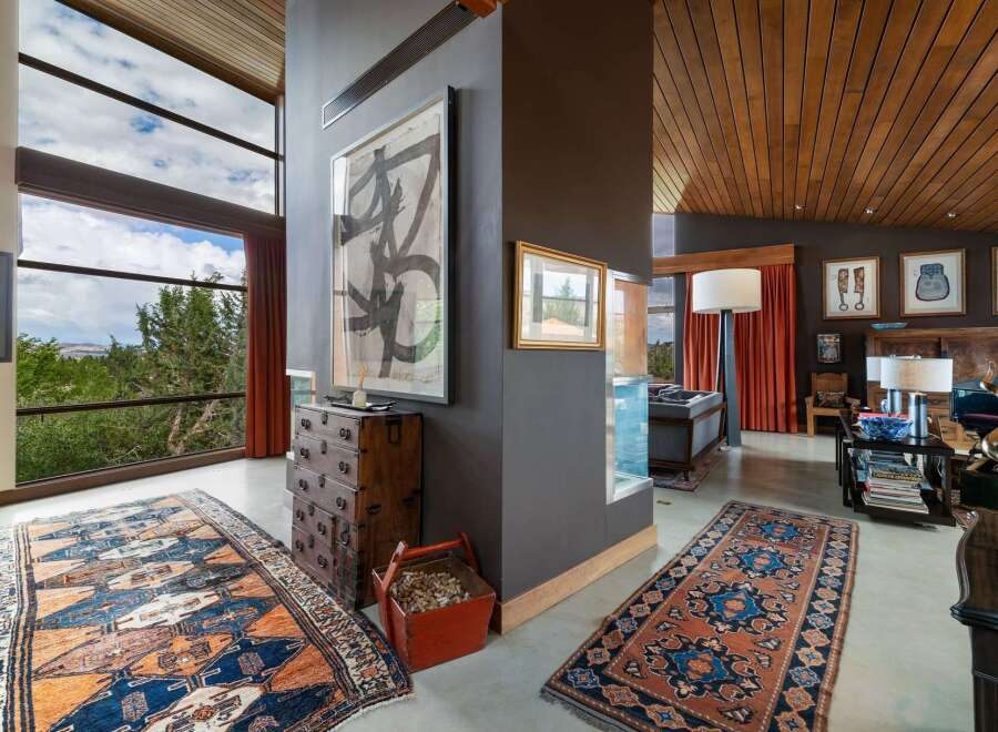 Experience breathtaking views through expansive windows in this stunning living space, featuring a dramatic high ceiling with rich wood paneling.