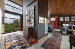 Experience breathtaking views through expansive windows in this stunning living space, featuring a dramatic high ceiling with rich wood paneling.