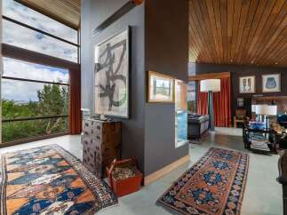 Experience breathtaking views through expansive windows in this stunning living space, featuring a dramatic high ceiling with rich wood paneling.