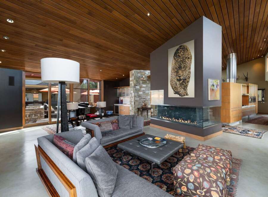 Experience luxury living in this stunning modern home featuring a dramatic floor-to-ceiling fireplace as the centerpiece of the living area.