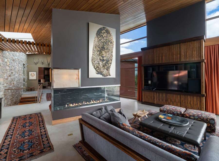 Experience luxury living in this stunning modern home featuring a dramatic double-sided fireplace as the centerpiece of the living area.