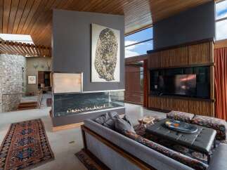 Experience luxury living in this stunning modern home featuring a dramatic double-sided fireplace as the centerpiece of the living area.
