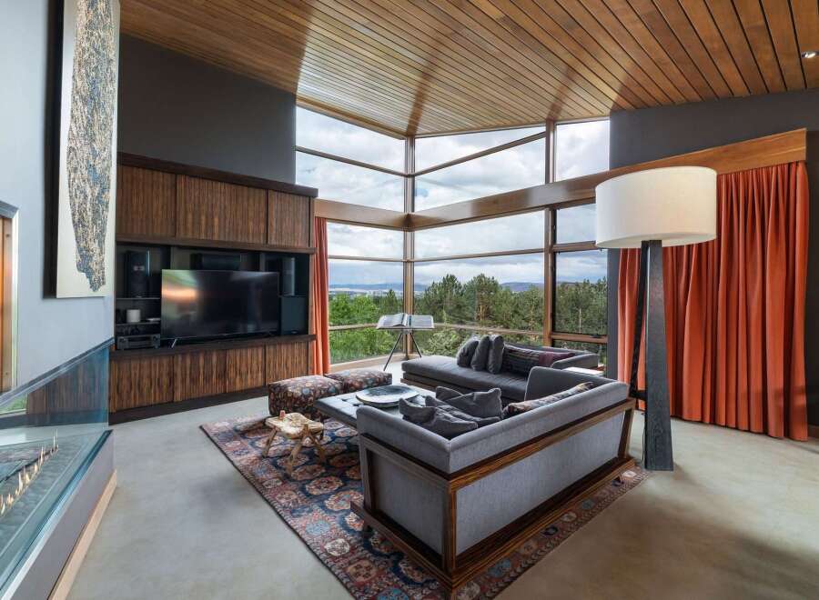 Experience breathtaking panoramic views from this stunning living room, featuring expansive floor-to-ceiling windows that frame a lush forest landscape.