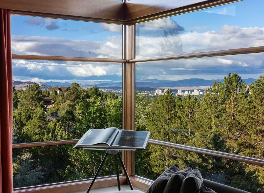 Experience breathtaking panoramic views from this stunning property, featuring expansive corner windows that frame a picturesque landscape of rolling hills, lush forests, and a distant city skyline.