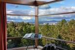 Experience breathtaking panoramic views from this stunning property, featuring expansive corner windows that frame a picturesque landscape of rolling hills, lush forests, and a distant city skyline.