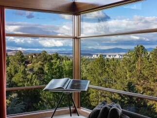 Experience breathtaking panoramic views from this stunning property, featuring expansive corner windows that frame a picturesque landscape of rolling hills, lush forests, and a distant city skyline.