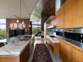 Experience modern luxury in this stunning open-concept kitchen, featuring sleek marble countertops and warm wood cabinetry.